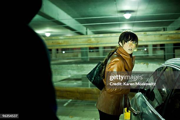 woman surprised by hooded man in parking garage - victim silhouette stock pictures, royalty-free photos & images