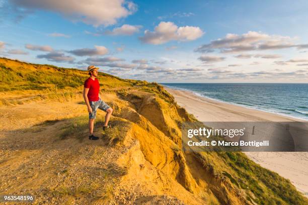 tourist admiring the sunset on the rotes kliff (red cliffs), sylt island. - kampen sylt stock-fotos und bilder