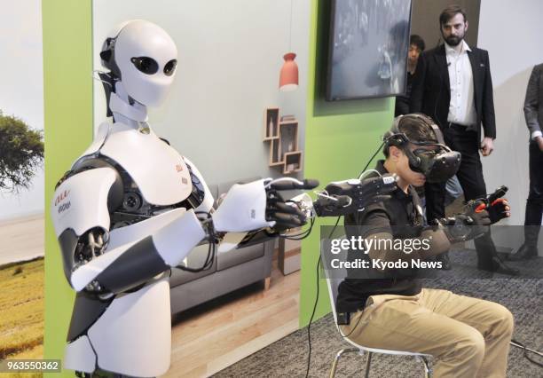 Man remotely controls a humanoid robot, developed by KDDI Corp. And Telexistence Inc., via specialized goggles and gloves in Tokyo on May 29, 2018....