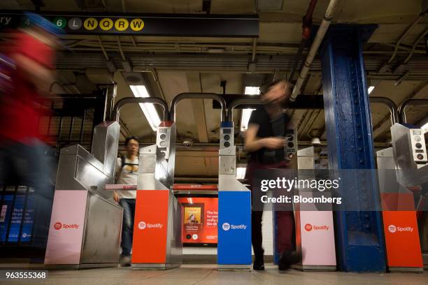 Commuters exit turnstiles displaying Spotify Technology SA advertisements at the Union Square subway station in New York, U.S., on Friday, May 25,...