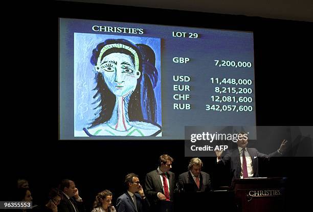 An auctioneer speaks as a portrait entitled 'Tete de femme' or 'Head of a Woman In Profile' by Spanish artist Pablo Picasso is displayed on a screen...