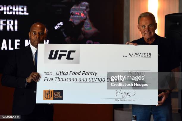 Senior director of communications Dave Lockett presents a donation to Russell Brooks, president of the Utica Food Pantry, during a UFC press...