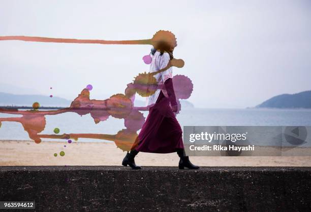 a woman walking along the beach which became a painting where the head turned red - depression frau stock-fotos und bilder