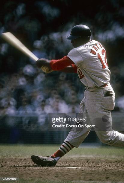 First Baseman Bill White of the St. Louis Cardinals swings and watches the flight of his ball during a circa 1960's Major League Baseball game. White...