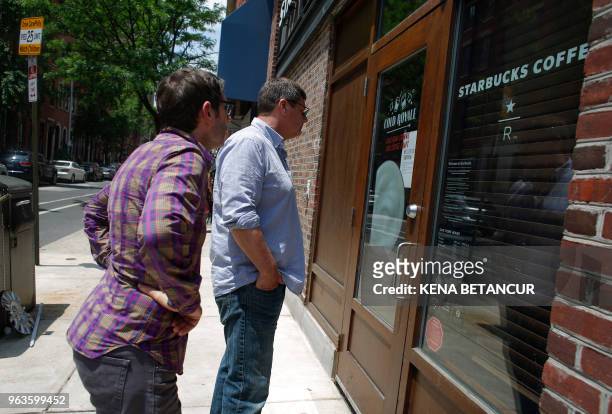 Customers read a "store closed" note is displayed at the Spruce St. Starbucks store on May 29, 2018 in Philadelphia, Pennsylvania. - Starbucks is...