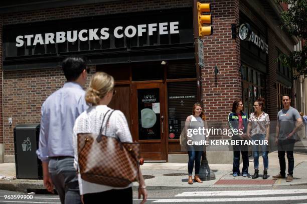 Pedestrians walk outside the closed Spruce St. Starbucks store on May 29, 2018 in Philadelphia, Pennsylvania. - Starbucks is closing more than 8,000...