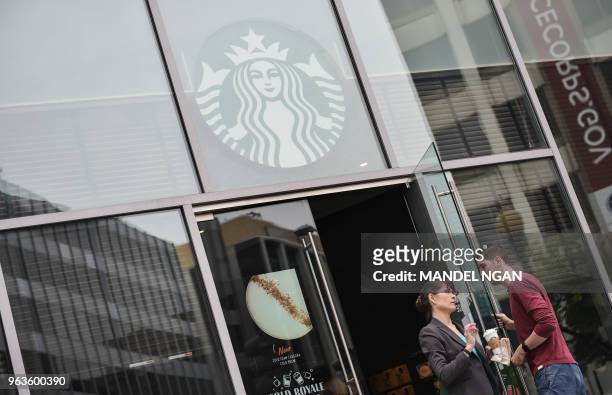 Customer leaving a Starbucks warns a man that the store will be closing shortly on May 29, 2018 in Washington, DC. - Starbucks is closing more than...