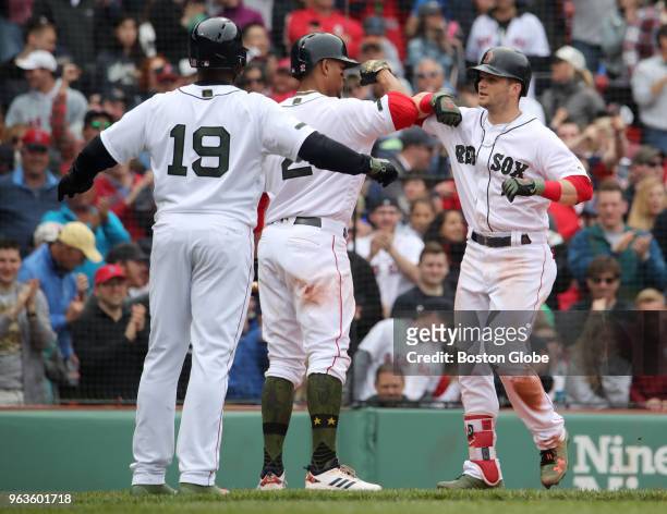 Boston Red Sox player Andrew Benintendi is greeted at home plate after hitting a three-run home run by teammates Xander Bogaerts and Jackie Bradley...