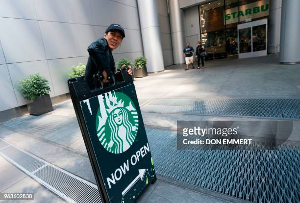Manhattan Starbucks employee puts away a sidewalk sign as the stores closes May 29, 2018 in New York. - Starbucks closed more than 8,000 stores...