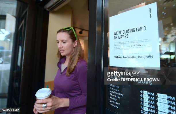Starbucks customer steps out of a store with her purchase in Los Angeles on May 29 beside a sign posted notifying customers of its closure. -...