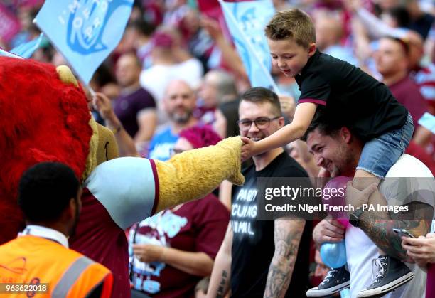 Young Aston Villa fan in the stands greets Aston Villa mascot Hercules the Lion during the Sky Bet Championship Final at Wembley Stadium, London.