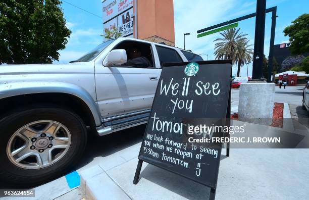 Driver in a vehicle pulls up to a drive-thru line at a Starbucks in Rosemead, California on May 29 where a sign advises customers of its closure in...