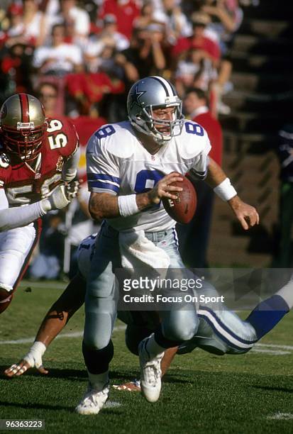 Quarterback Troy Aikam of the Dallas Cowboys scrambles out of the pocket with defensive end Chris Doleman of the San Francisco 49ers putting the...