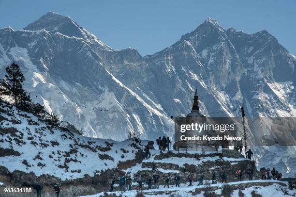 Photo taken in March 2015 shows trekkers and Sherpas walking on a trail near Namche Bazaar in eastern Nepal, with Mt. Everest and Mt. Lhotse seen in...
