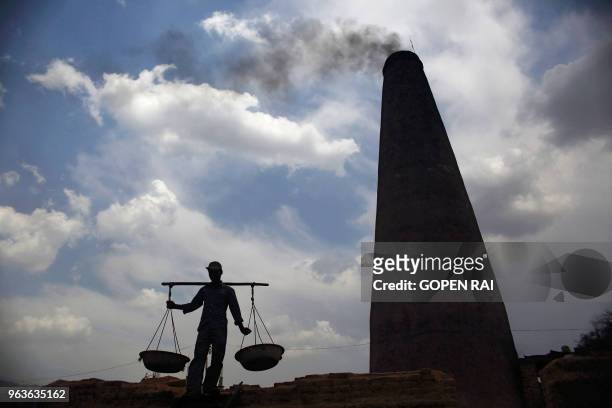 In this photograph taken on May 10 a Nepali worker carries coal to fuel a bricks oven at a brick factory in Bhaktapur on the outskirts of Kathmandu....