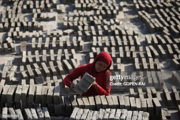 In this photograph taken on May 10 a Nepali labourer works at a brick factory in Bhaktapur, on the outskirts of Kathmandu. Below a sky darkened by...