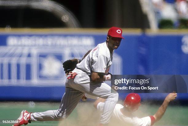 S: Shortstop Barry Larkin of the Cincinnati Reds aviods the runner of the Philadelphia Phillies to get his throw off to first base during a circa...