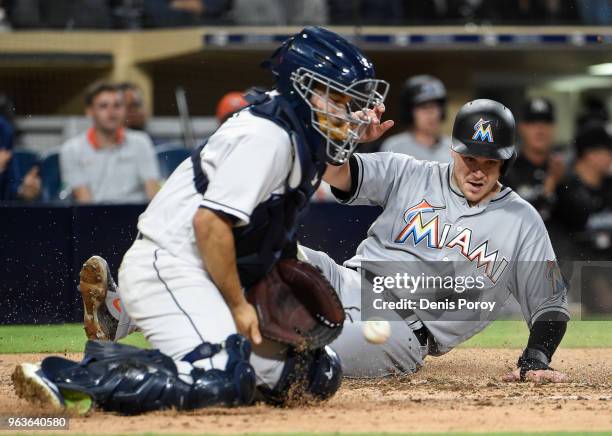 Brian Anderson of the Miami Marlins scores ahead of the throw to Raffy Lopez of the San Diego Padres during the sixth inning of a baseball game at...