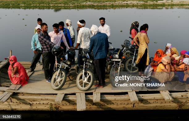 In this photograph taken on May 29 Indian commuters take a boat taxi across the Yamuna river in Manjhawali village, some 25kms from Faridabad. -...