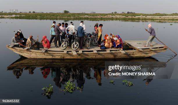 In this photograph taken on May 29 Indian commuters take a boat taxi across the Yamuna river in Manjhawali village, some 25kms from Faridabad. -...