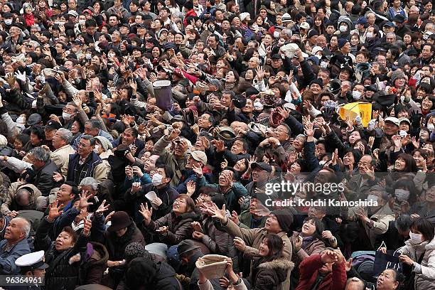 Visitors reach out for the beans thrown by sumo wrestlers, actors and actresses during a bean-scattering ceremony at Shinshoji Temple on February 3,...