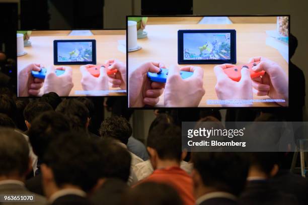 Members of the media watch a video presentation during a Pokemon Co. News conference where the company unveiled the video games Pokemon: Let's Go...
