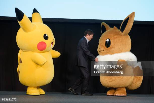 Tsunekazu Ishihara, chief executive officer of Pokemon Co., appears on the stage with Pokomon characters Pikachu, left, and Eevee during a Pokemon...