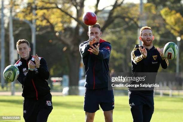 St Kilda's Ray Connellan, Qantas Wallabies superboot Reece Hodge and Hawthorn's Conor Glass pose outside AAMI park on May 30, 2018 in Melbourne,...