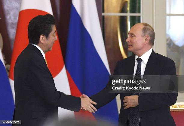 Russian President Vladimir Putin and Japanese Prime Minister Shinzo Abe shake hands after a joint press conference at the Kremlin in Moscow on May...