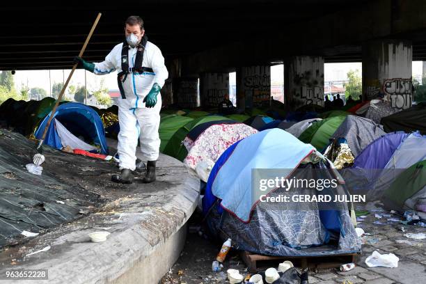 Worker cleans up the Millenaire migrants makeshift camp along the Canal de Saint-Denis near Porte de la Villette, northern Paris, following its...