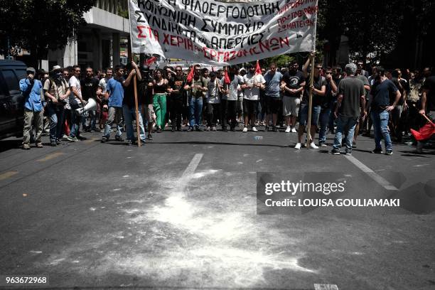 Leftist protesters stand behind tear gas thrown by police in Athens during a demonstration marking a 24-hour general strike on May 30, 2018. -...