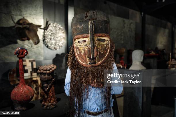 An employee poses with a large painted wood ceremonial mask during a press preview at Summers Place Auctions on May 30, 2018 in Billingshurst,...