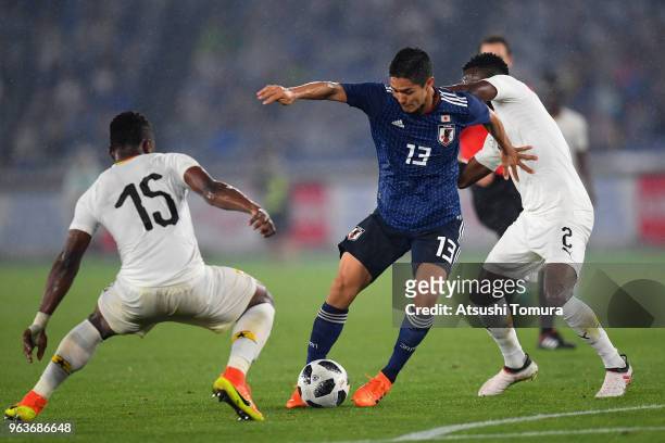 Yoshinori Muto of Japan controls the ball under pressure of Rashid Sumaila and Joseph Larweh Attamah of Ghana during the international friendly match...