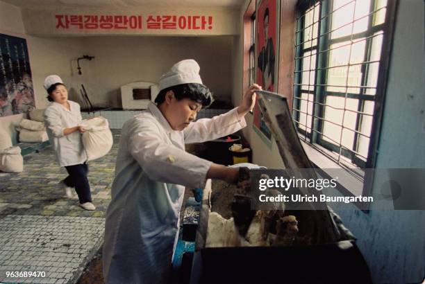 Bakers in a bakery in Hwasan. On the wall a propaganda poster.