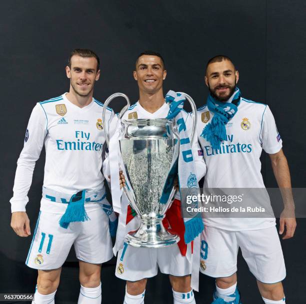 Cristiano Ronaldo of Real Madrid CF holds the trophy as he poses for a picture with his teammates Karim Benzema and Gareth Bale during the...