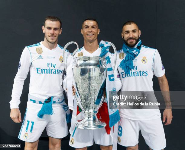 Cristiano Ronaldo of Real Madrid CF holds the trophy as he poses for a picture with his teammates Karim Benzema and Gareth Bale during the...