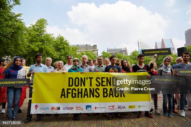 Afghan refugees and activists hold a banner and boards reading "Don't send Afghans back" as human rights group Amnesty International hand over a...