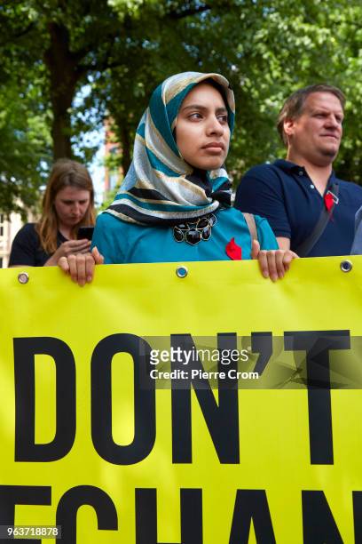 An Afghan refugee holds a banner as human rights group Amnesty International hand over a petition signed by more the 68,000 people to the Dutch...