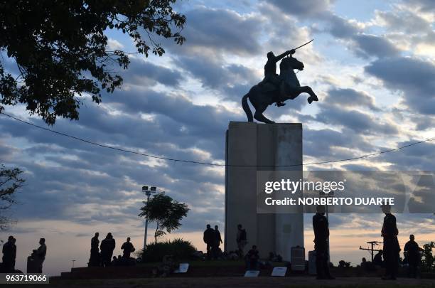 Police officers are silhouetted against a cloudy sky as they stand guard at a square in the surroundings of the Congress in Asuncion on May 30 after...