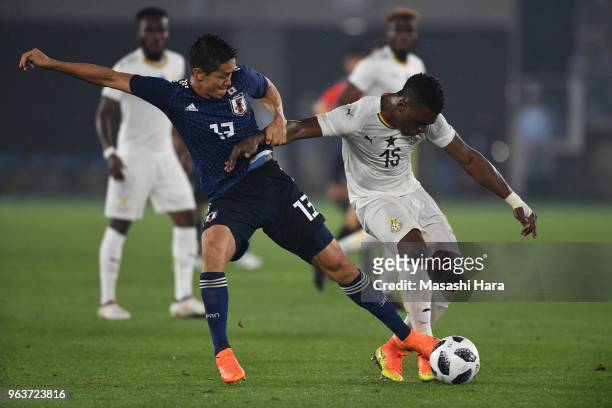Rashid Sumaila of Ghana and Yoshinori Muto of Japan compete for the ball during the international friendly match between Japan and Ghana at Nissan...