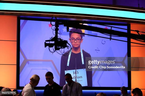 Adrian Beltran of Yigo, Guam, appears on a giant television screen as he participates in the third round of the 91st Scripps National Spelling Bee at...