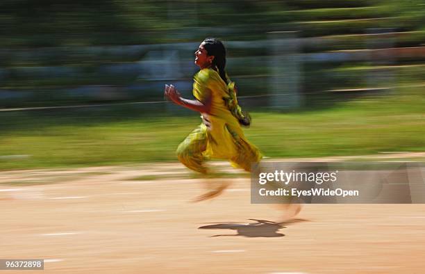 Young indian women are sprinting in a barefoot relay race, some are wearing the traditional long female salwar kameez dress, at a sports competition...