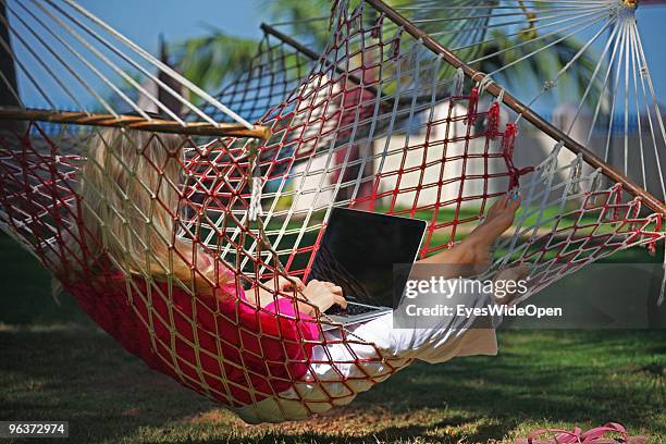 Woman lying in a hammock and working with a notebook on January 12, 2010 in Varkala near Trivandrum, Kerala, India.