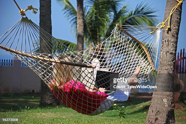 Woman lying in a hammock and working with a notebook on January 12, 2010 in Varkala near Trivandrum, Kerala, India.