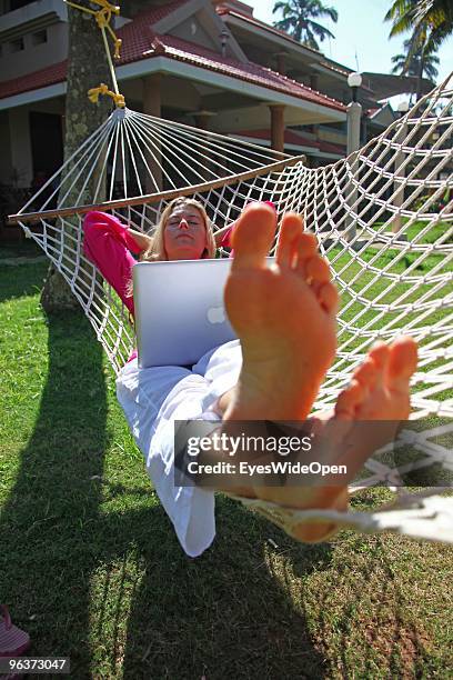 Woman lying in a hammock and working with a notebook on January 12, 2010 in Varkala near Trivandrum, Kerala, India.