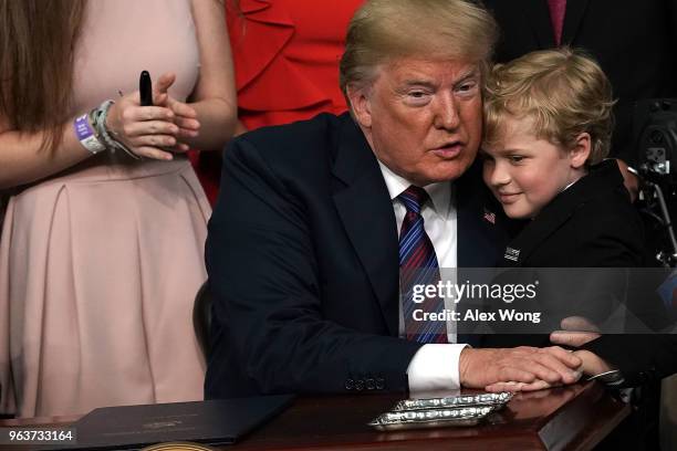 Duchenne Muscular Dystrophy patient Jordan McLinn of Indiana gives U.S. President Donald Trump a hug during a bill signing ceremony at the South...