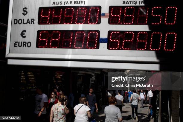 People pass a currency exchange board showing prices for the USD and Euro at the entrance to Istanbul's famous Grand Bazaar on May 30, 2018 in...
