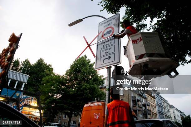 Worker removes a marker to validate a sign that bans access for older-model diesel cars on a street on May 30, 2018 in Hamburg, Germany. The city is...