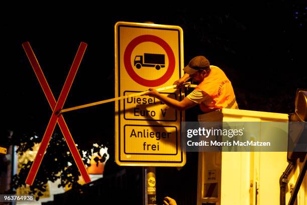 Worker removes a marker to validate a sign that bans access for older-model diesel cars on a street on May 30, 2018 in Hamburg, Germany. The city is...