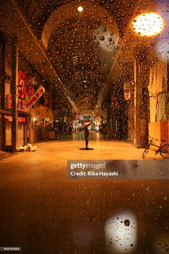 A woman standing with an umbrella in a shopping street